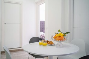 A dining table with a fruit bowl, two glasses of orange juice, and croissants. - Modern spacious apartment with terrace, balconies, solarium & gym (Sorrento)