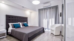A modern bedroom with a large bed, a white nightstand, a desk, and a chair. - Modern spacious apartment with terrace, balconies, solarium & gym (Sorrento)