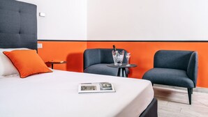 A hotel room with a bed, two armchairs, a small table with a drink, and a magazine on the bed. - Modern spacious apartment with terrace, balconies, solarium & gym (Sorrento)