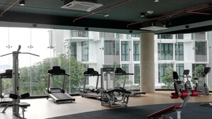 Et moderne fitnesscenter med forskellig træningsudstyr, store vinduer og udsigt til grøn natur.