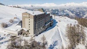 Un hotel grande con varios pisos y una pista de esquí al fondo.