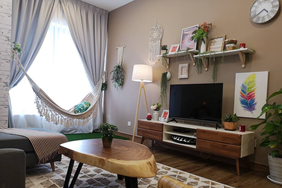 Moderni olohuone, jossa on sohva, puinen sohvapöytä, televisio ja riippukeinu.