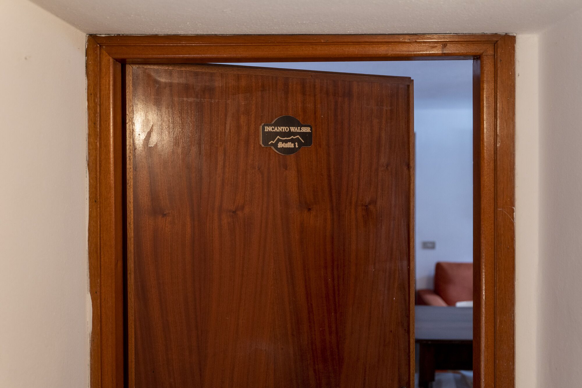 Een houten deur met een bordje waarop staat 'INCANTO WALSER Statu 1'.