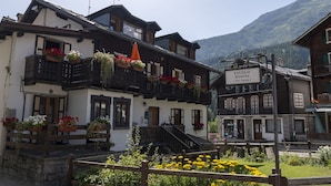 Un edificio de estilo chalete tradicional con un balcón decorado con flores, un letrero que dice 
