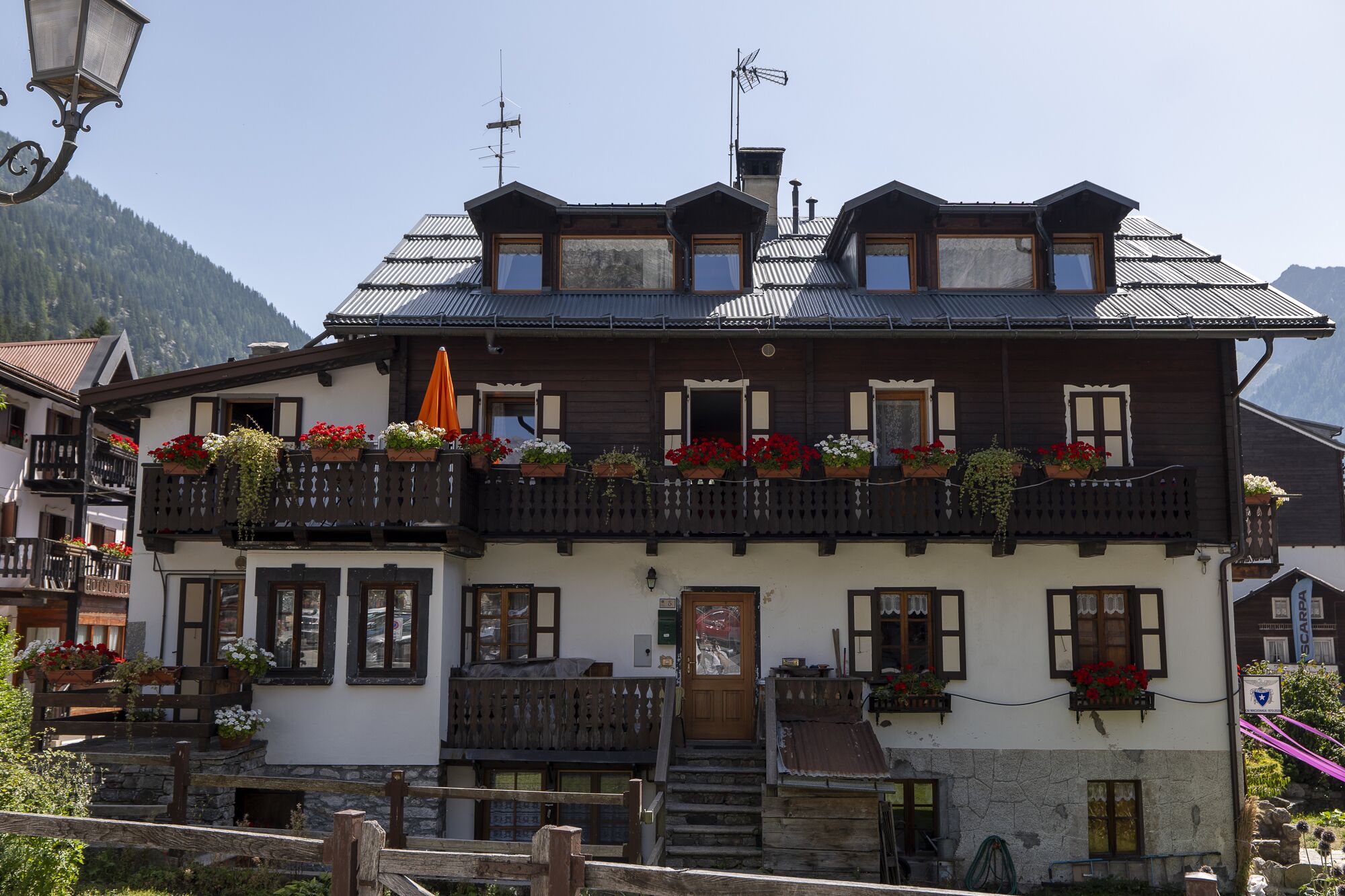 Ein traditionelles Chalet mit Holzfassade, mehreren Balkonen mit Blumenkästen und Bergblick.