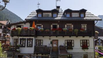 Ein traditionelles Chalet mit Holzfassade, mehreren Balkonen mit Blumenkästen und Bergblick.