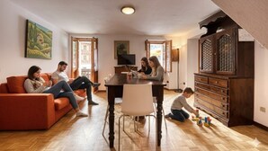 Una sala de estar con piso de madera, una mesa de comedor, un sofá y un aparador.