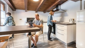 Una cocina moderna con vigas de madera, una zona de comedor y una persona usando una tableta.