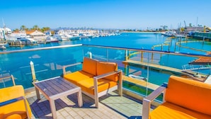 Ein Poolbereich mit orangefarbenen Sitzgelegenheiten und Blick auf eine Marina mit Booten.
