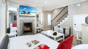 A modern hotel room with a fireplace, a television mounted on the wall, a staircase, and a dining area. - Awesome Multi Level - Large Patio - Fast WIFI - Work Desks - Self Check In! (CM-2) (Costa Mesa)