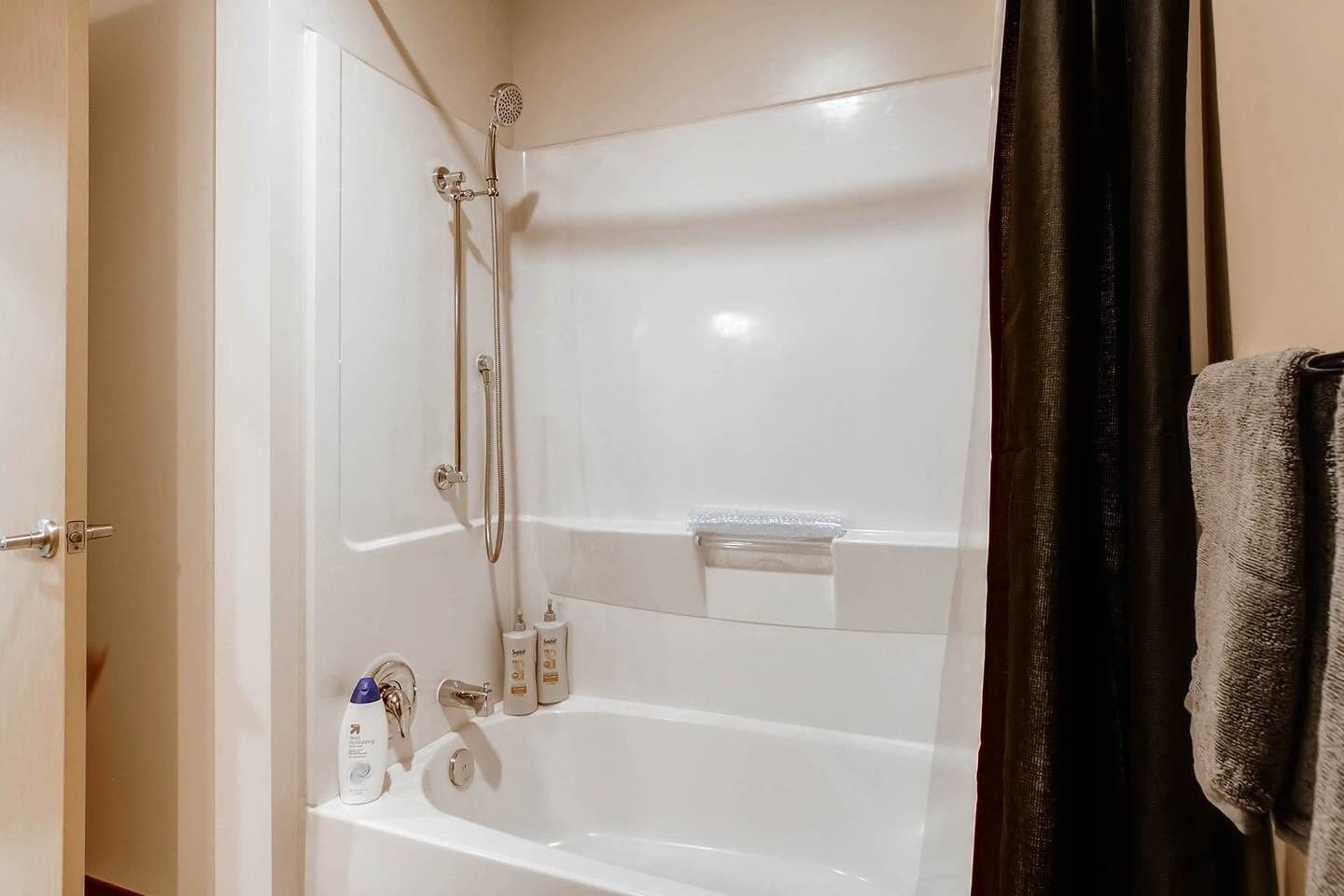 A bathroom with a bathtub, a shower, and a towel rack.