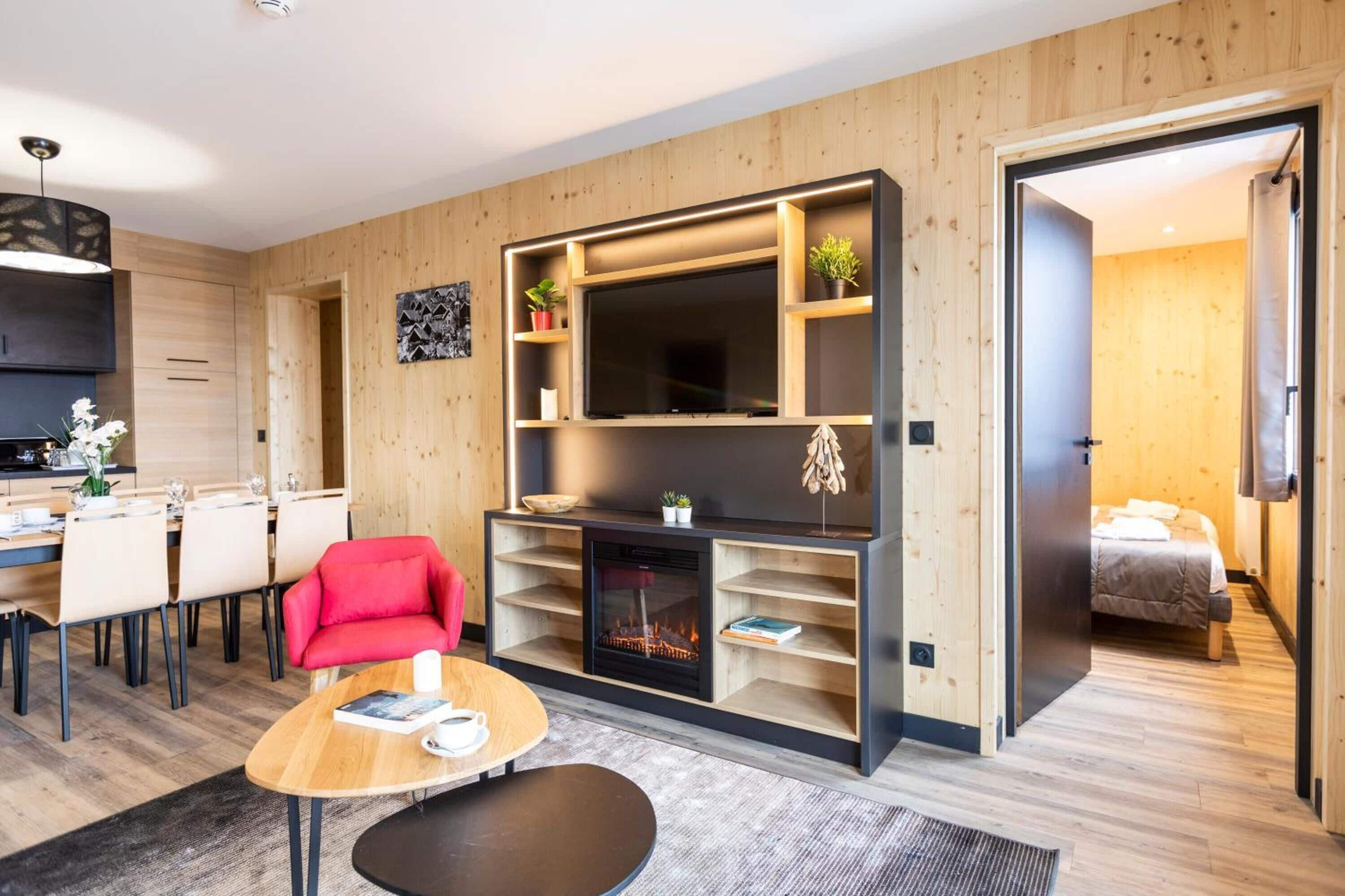Un salon moderne avec une cheminée, un téléviseur et un coin repas comprenant des chaises et une table.