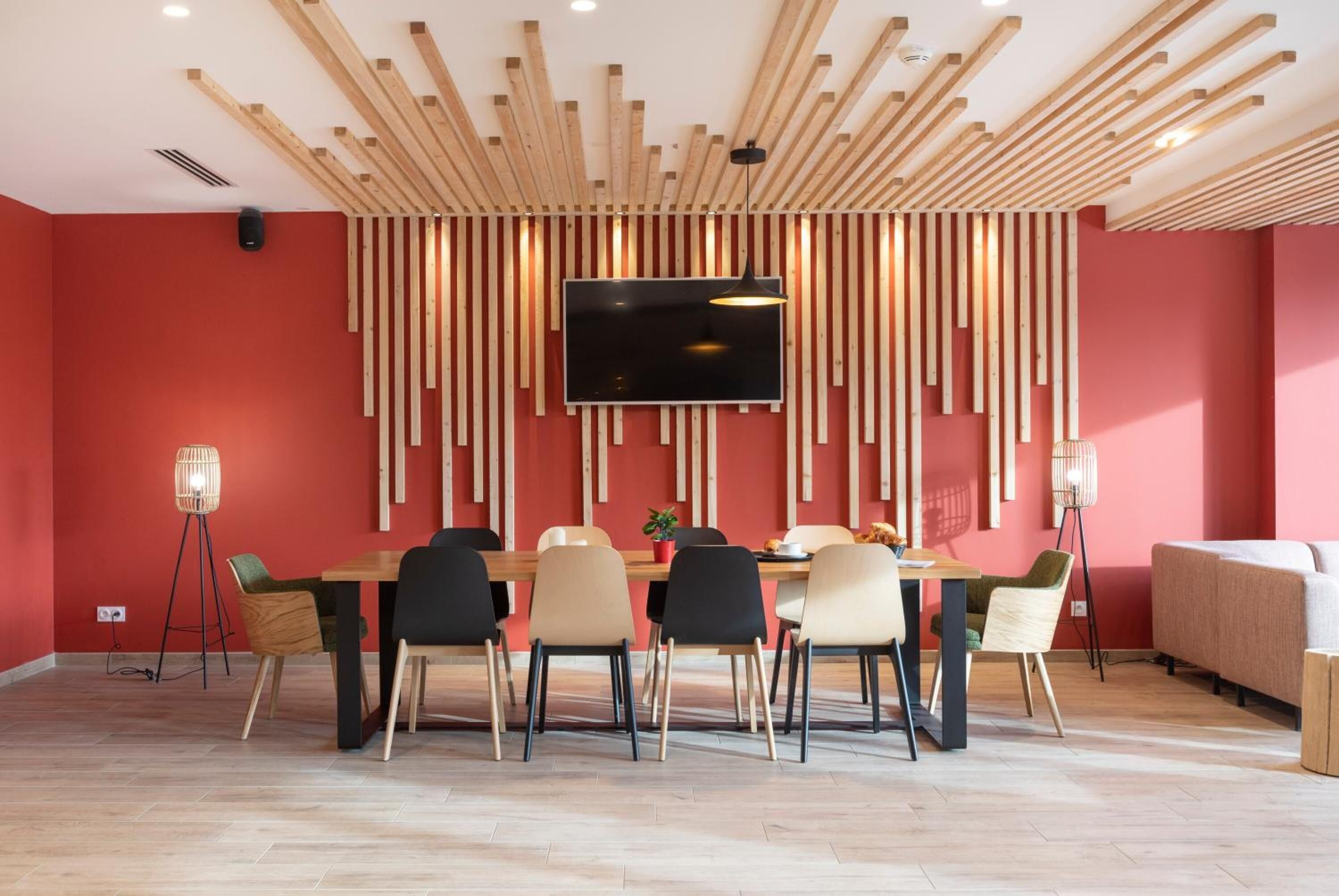 A modern dining area with a wooden ceiling, a large flat-screen TV, and a dining table with chairs.