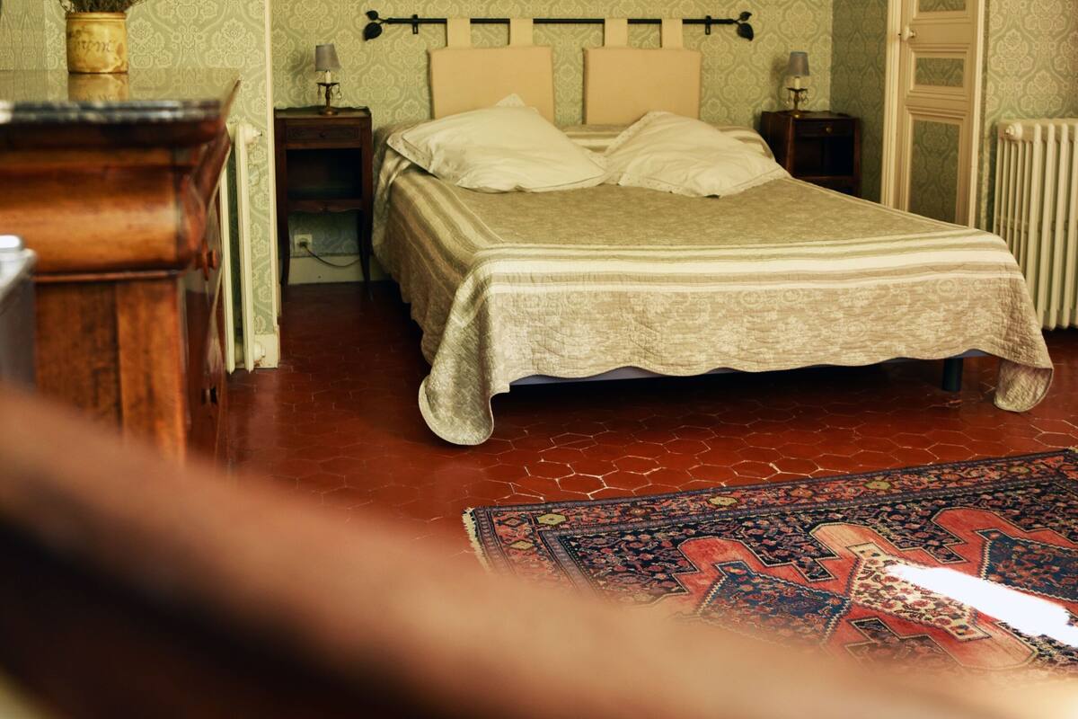 A bedroom with a bed, a nightstand, a dresser, and a radiator.