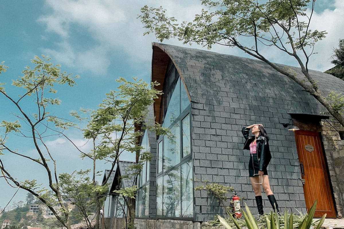 Een modern gebouw met een gebogen dak en grote ramen, omgeven door bomen en groen.