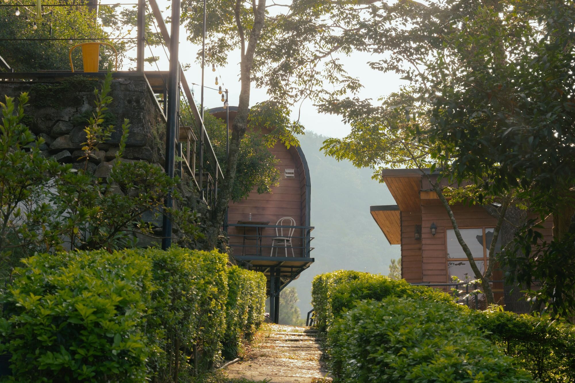 Un sentier mène à un bâtiment rustique doté d’un mur en pierre et d’une structure en bois.