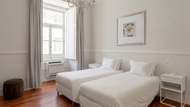 A bedroom with two beds, a chandelier, a framed picture, and a window with curtains. - JOIVY Astonishing 4BR home in Baixa,  5mins to Santa Justa Lift (Lisboa)