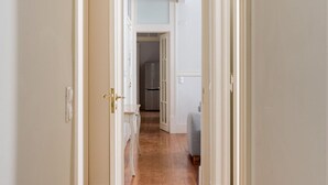 A narrow hallway with a door on the left, a small table and chair, and a refrigerator in the background. - JOIVY Astonishing 4BR home in Baixa,  5mins to Santa Justa Lift (Lisboa)