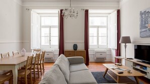 A living room with a sofa, dining table, chairs, a TV, and a chandelier. - JOIVY Astonishing 4BR home in Baixa,  5mins to Santa Justa Lift (Lisboa)