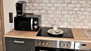 Una cocina compacta con horno empotrado, cafetera y microondas.