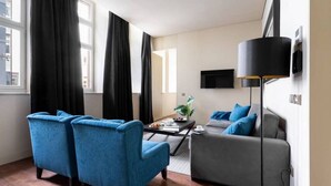 A modern living room with a sofa, two armchairs, a coffee table, and a TV mounted on the wall. - JOIVY Spacious 1-bed Apt nearby Time Out Market &subway (Lisboa)