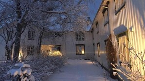 A snow-covered courtyard with buildings, bare trees, and a clear sky. - Skagen Gaard (Bodo)