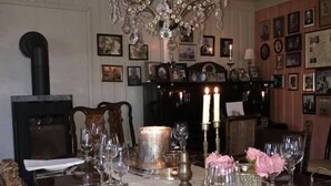A dining room with a long wooden table set for a meal, a chandelier, and a fireplace. - Skagen Gaard (Bodo)