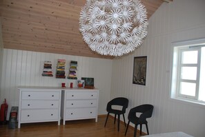 Cozy retreat with a dresser, table, and two chairs, featuring a large light fixture and a window.