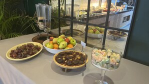 A buffet table with various food items including grapes, pears, oranges, and a dessert glass. - Pure Blanche Hotel (Antalya)