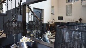 A staircase with ornate black railings and a mirrored wall reflecting the room. - La petite Aiguebonne (Allex)