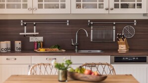 Una cocina moderna con armarios blancos, un lavamanos de acero inoxidable y un lavavajillas empotrado.