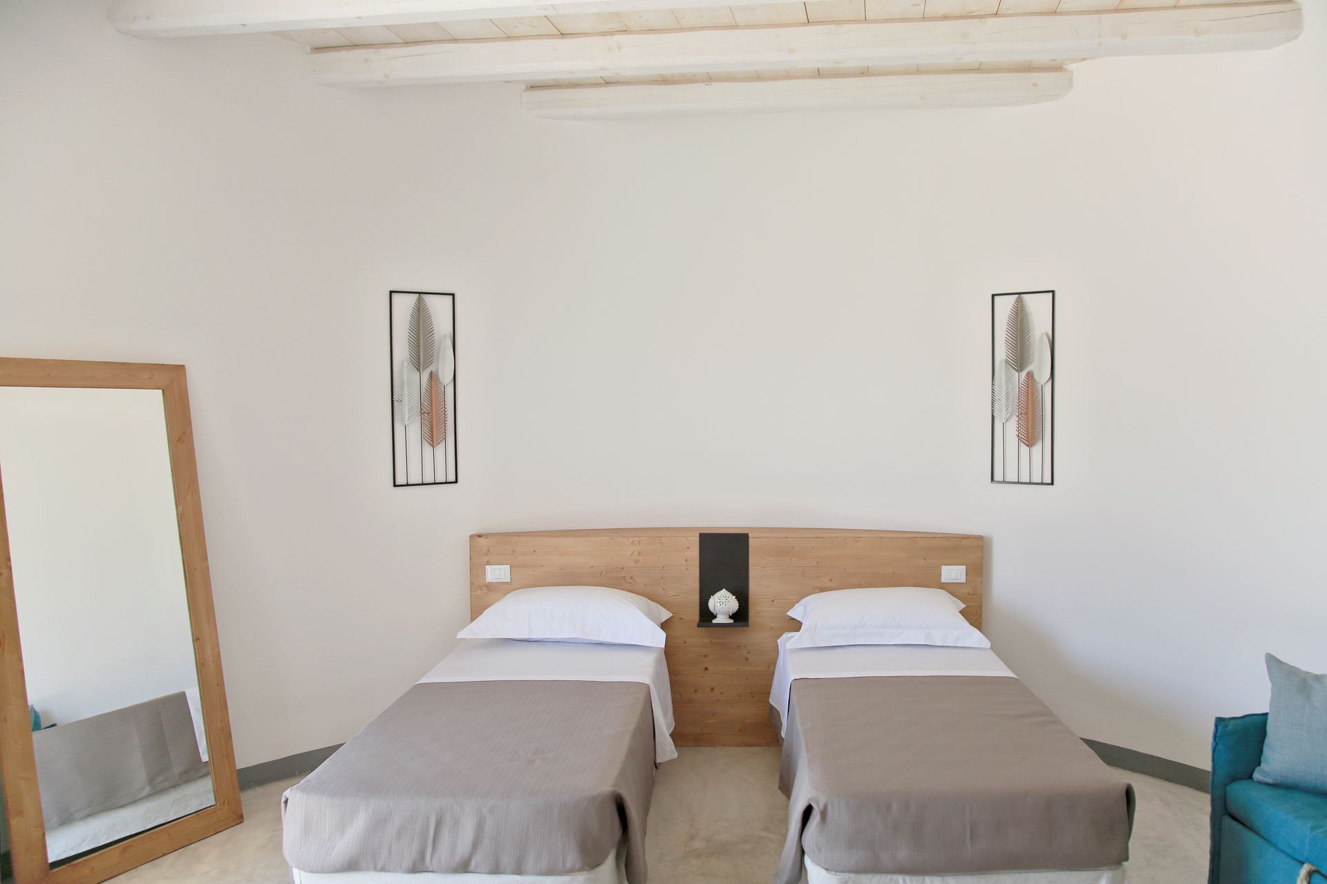 A bedroom with two single beds, a wooden headboard, a large mirror, and wall art.