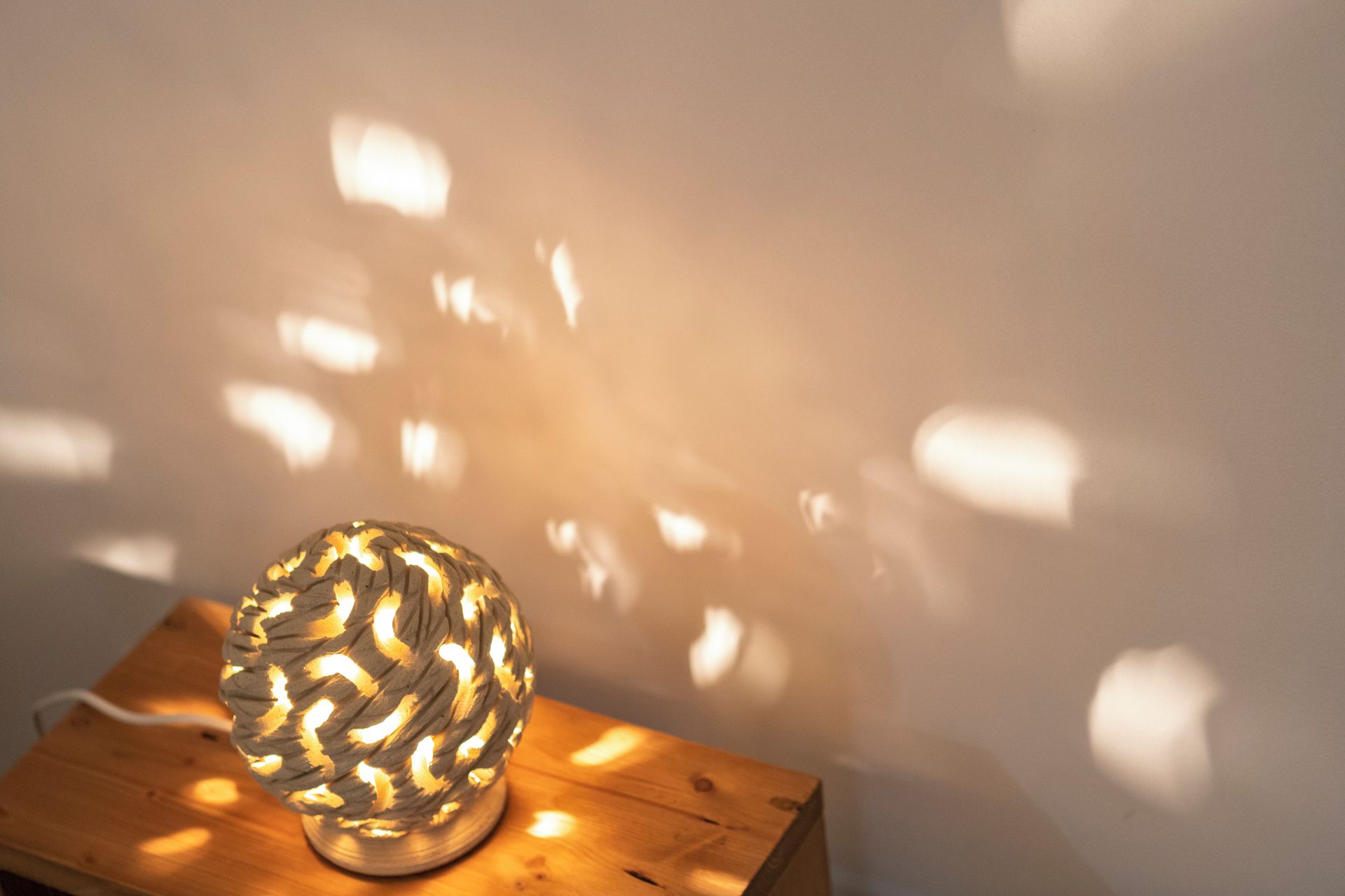 Eine runde Lampe mit strukturierter Oberfläche auf einer Holztischplatte.