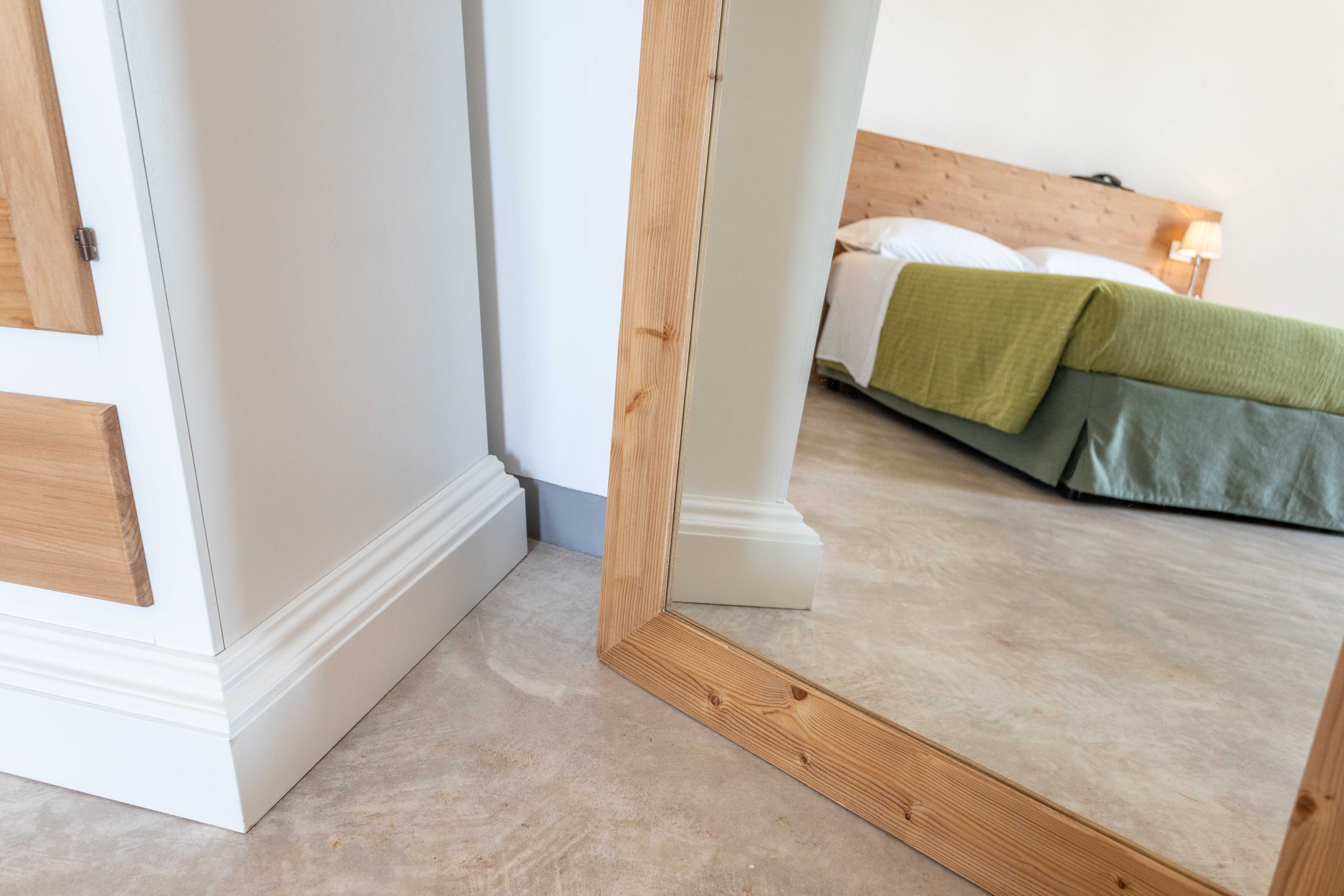 Un dormitorio con una cama, cabecera de madera y pared blanca.