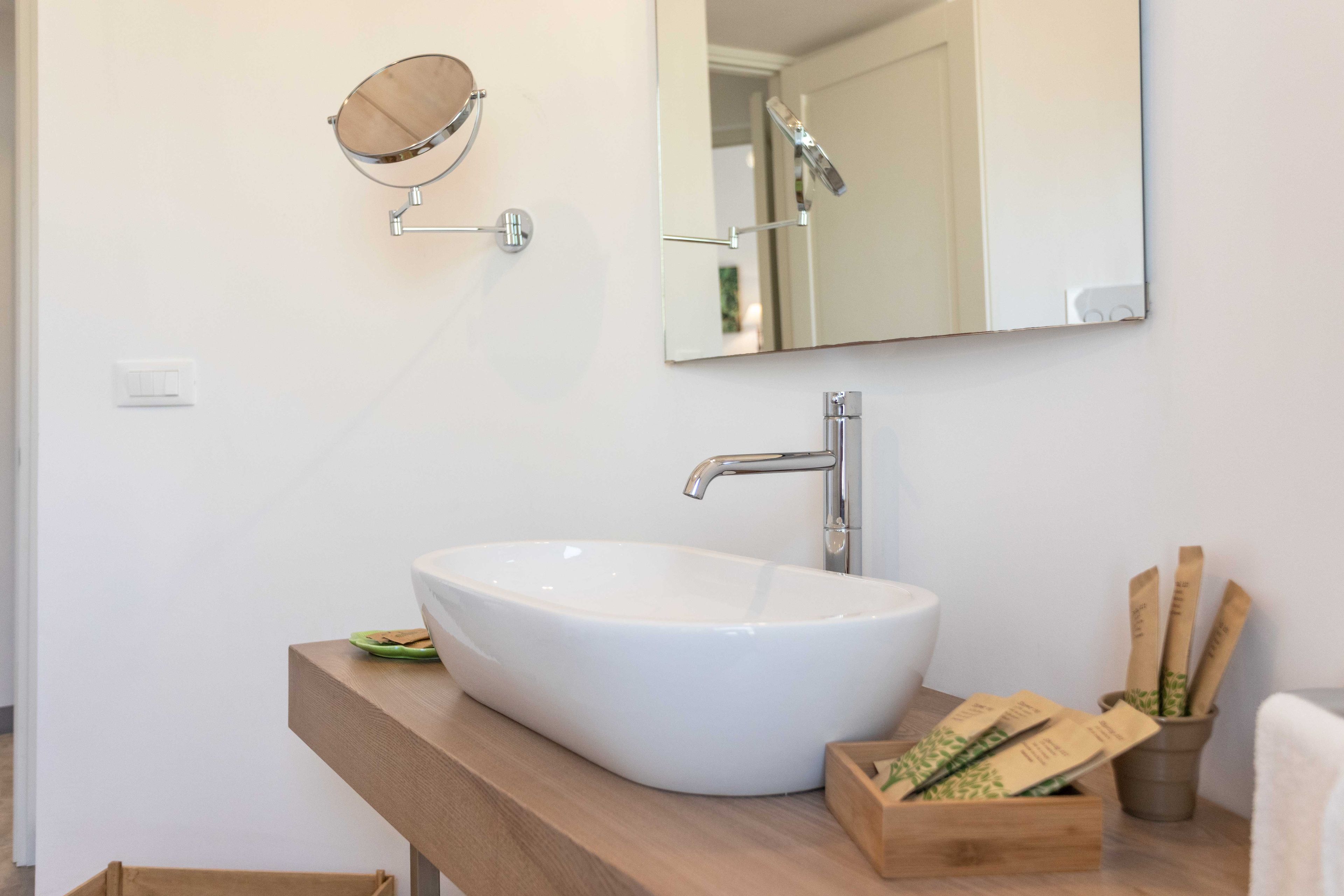 A bathroom with a white sink, a mirror, and a wooden vanity.