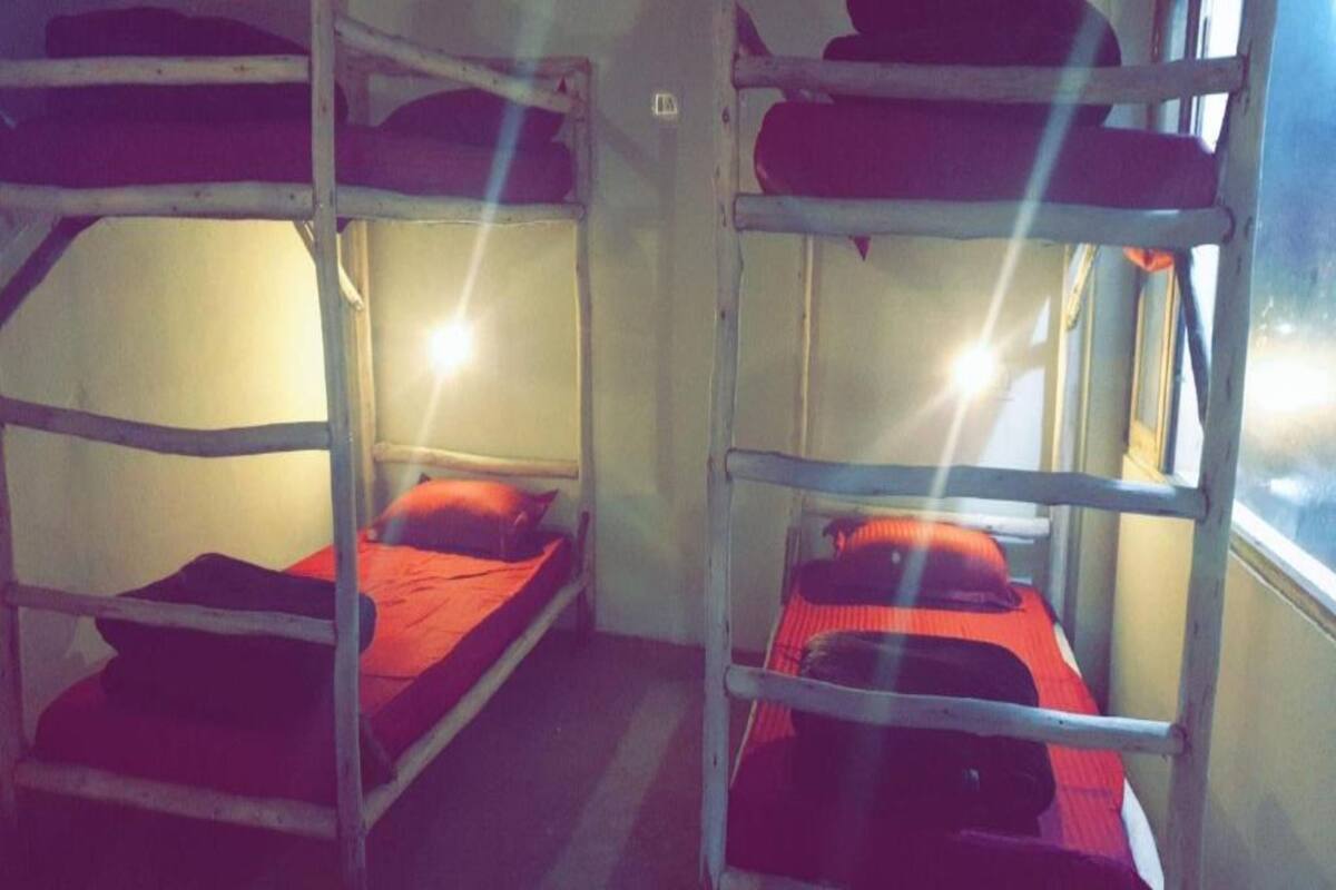 Bunk beds with red bedding in a room with a window.