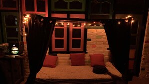 A bed with a canopy, red pillows, and a string of lights. - The Hostalgic Jibhi - Hostel (Banjar)