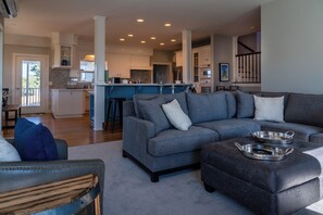 A modern living room with a grey sectional sofa, a leather armchair, and a coffee table with a tray.