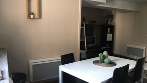 Un coin repas avec une table blanche, des chaises noires, une petite plante en pot et un cactus servant de décoration centrale.