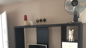 Un salon moderne avec un meuble de rangement noir pour appareils électroniques, un téléviseur à écran plat, un petit meuble blanc et un globe décoratif accroché au mur.