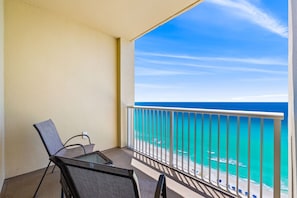 Uma varanda com vista para o oceano, uma cadeira e uma mesa.