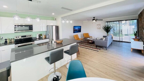 A modern kitchen with stainless steel appliances, a central island, and a dining area with bar stools. - Walkable Old Town Scottsdale, Heated Poolside Mid Century Condo. (Scottsdale)