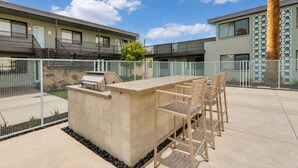 An outdoor patio with a grill, seating, and a view of a modern building. - Walkable Old Town Scottsdale, Heated Poolside Mid Century Condo. (Scottsdale)