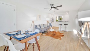 A modern living room with a dining area, a sofa, a ceiling fan, and a kitchen in the background. - Pool front Condo, steps from memorable Old Town. (Scottsdale)