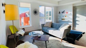 Una sala de estar moderna con un sofá, sillones, una mesa de centro y una lámpara.