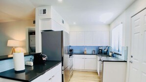Una cocina moderna con armarios blancos, encimera negra y salpicadero azul.