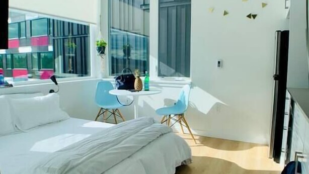 A modern bedroom with a large bed, a small desk, and a window with a view of buildings. - Unique poolside studio -  less than a mile to Old Town (Scottsdale)