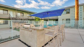 An outdoor patio with a grill, seating, and a blue umbrella. - Unique poolside studio -  less than a mile to Old Town (Scottsdale)