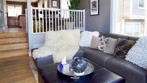 Un soggiorno moderno con un divano in pelle scura, un tappeto soffice bianco e un tavolino da caffè con un vassoio decorativo.