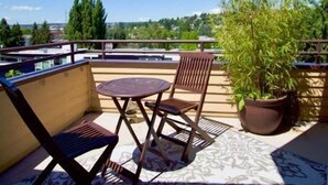 Un balcone con una sedia di legno, un tavolino e una pianta in vaso.